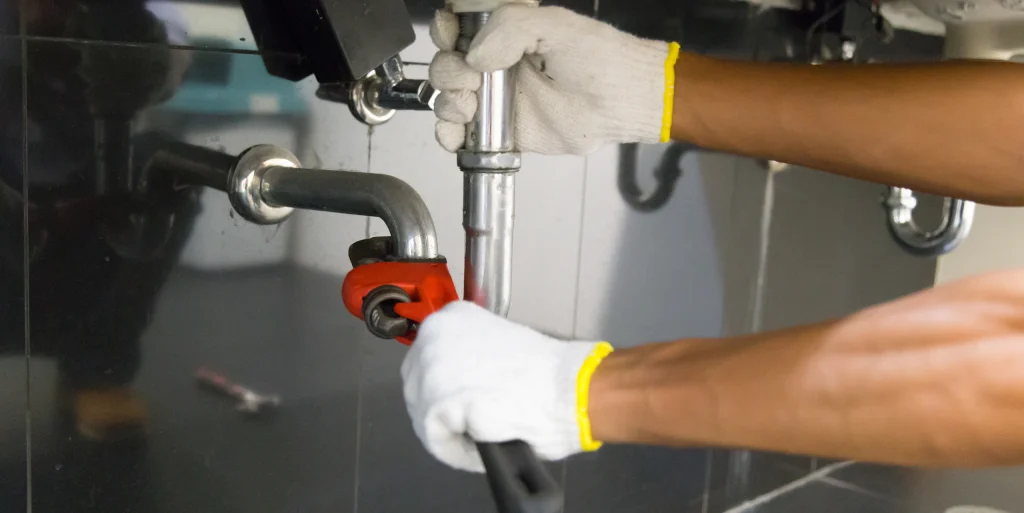plumber fixing white sink pipe with adjustable wrench